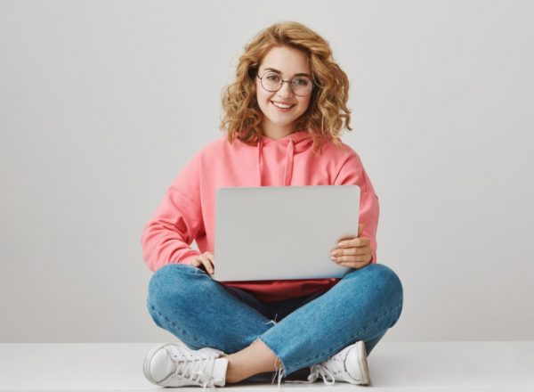 cute-freelance-girl-using-laptop-sitting-floor-smiling-min