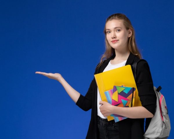 front-view-female-student-white-shirt-black-jacket-wearing-backpack-holding-files-with-copybooks-blue-wall-college-university-lessons-min
