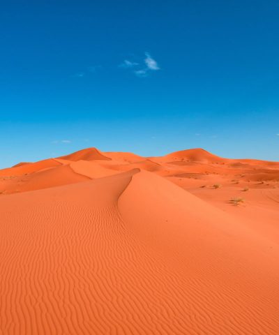 vertical-image-landscape-orange-sand-dunes-against-blue-sky-min